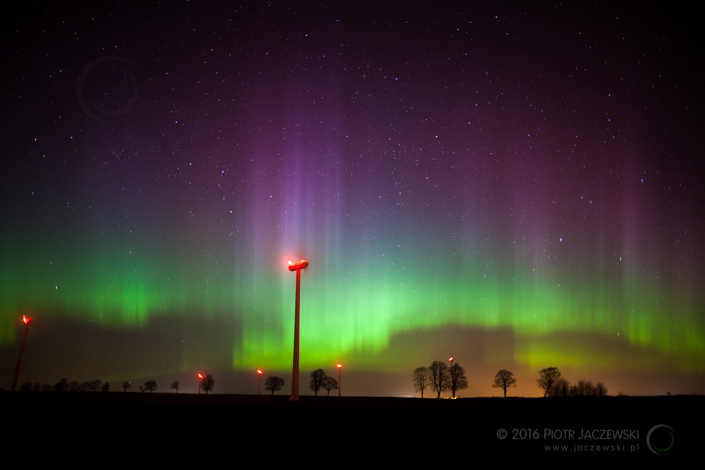 A wind turbine at night with strong Aurora on the sky